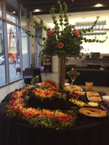 Fruits laid out beautifully on a table with a big flower centerpiece
