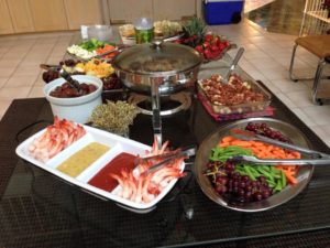 A table with various savory dishes and bowls of fruits